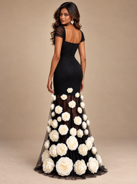 Floor-length black sheer skirt decorated with large white rose appliques on a Jovellee evening gown