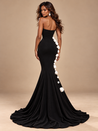 Floor-length flared skirt of a black Jovellee mermaid prom dress with white rose decorations