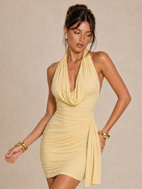 Three-quarter view of the Jovellee Elara butter yellow chiffon mini dress with draped halter neck and side sash