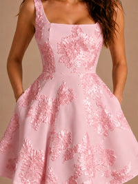 Detail of blush pink 3D floral applique homecoming dress showing raised floral fabric, square neckline, and flared skirt.